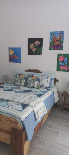 a bed in a bedroom with paintings on the wall at Casa Katharina in Cahuita
