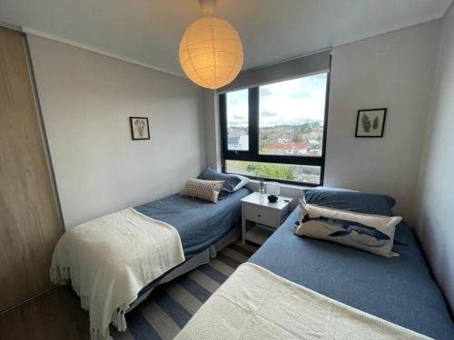 a bedroom with two beds and a large window at Acogedor departamento in Puerto Varas