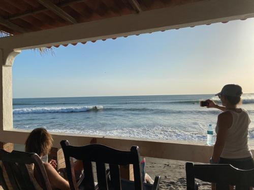 a woman taking a picture of the ocean from the beach at SOLID Surf Camp Hostel Nicaragua in Transito