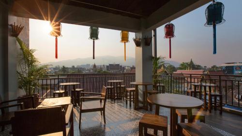 a restaurant with tables and chairs on a balcony at Green Tiger House in Chiang Mai