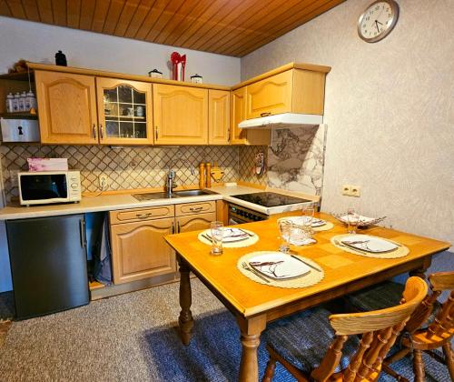 una cucina con armadi in legno e un tavolo in legno con sedie di Gemütliche Ferienwohunung a Bad Grund