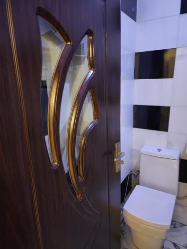 a bathroom with a toilet and a wooden door at The Milton Apartment in Ikeja