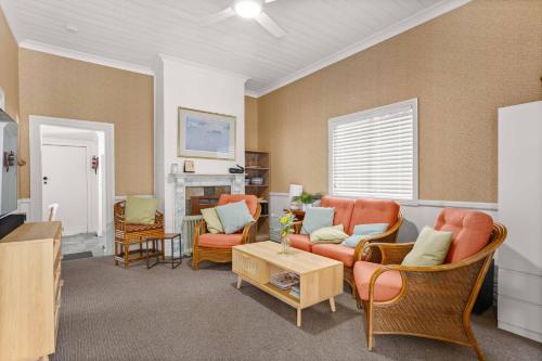 a living room with orange chairs and a fireplace at The Gunyah by Experience Jervis Bay in Huskisson