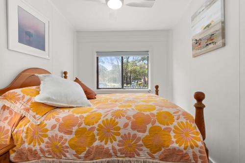 a bedroom with a bed with a colorful comforter and a window at The Gunyah by Experience Jervis Bay in Huskisson