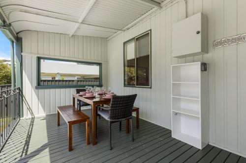 a dining room with a table and chairs on a deck at The Gunyah by Experience Jervis Bay in Huskisson