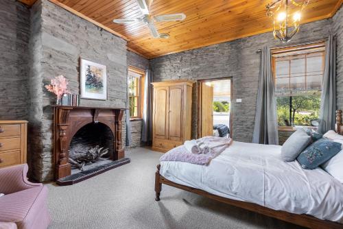 1 dormitorio con 1 cama grande y chimenea en Reillys Wines Heritage Cottages, en Mintaro
