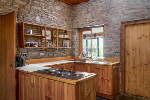 cocina con armarios de madera y horno con fogones en Reillys Wines Heritage Cottages, en Mintaro