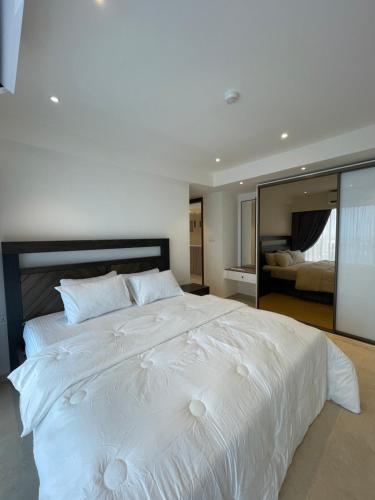 a large white bed in a bedroom with a mirror at Solaris Appartment 5&7th floor in Accra