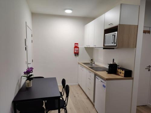 a kitchen with white cabinets and a table with chairs at Corso studio 0303 in Leuven