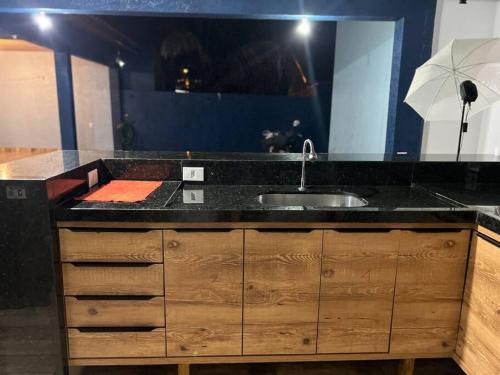 a kitchen with a sink and a black counter top at Acomodação Três Fronteiras Foz in Foz do Iguaçu