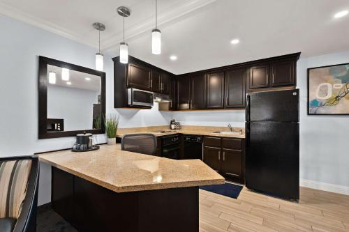 a kitchen with wooden cabinets and a black refrigerator at Best Western Plus Manhattan Beach Hotel in Manhattan Beach