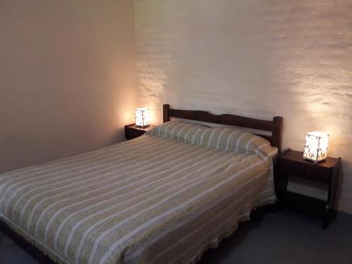Un dormitorio con una cama con dos luces. en Departamentos Don Carlos en Villa Cura Brochero
