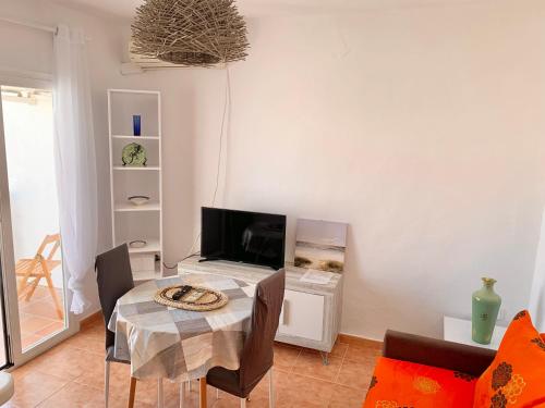 uma sala de estar com uma mesa e uma televisão em APT CalmaCabana a 50m dal mare em Es Pujols