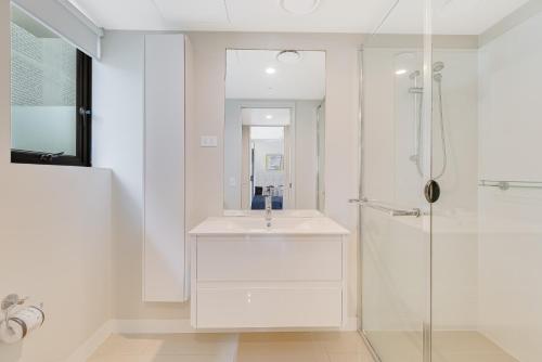 a white bathroom with a sink and a shower at Pure Kirra in Gold Coast