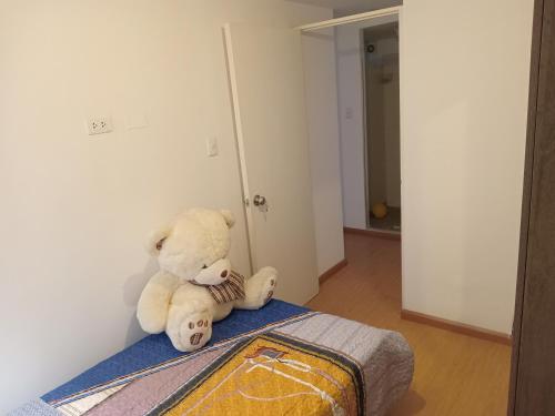 um urso de peluche sentado em cima de uma cama em Departamento amoblado 9vno piso em Lima