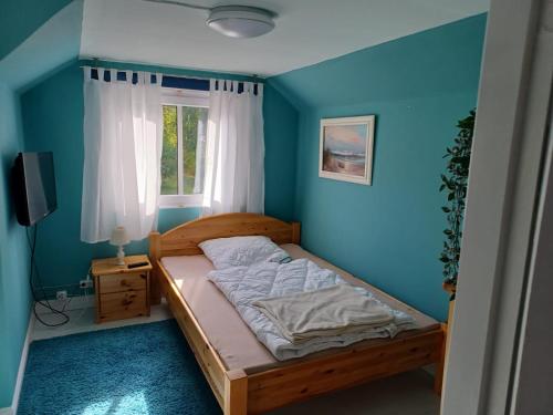 - une chambre avec un lit et un mur bleu dans l'établissement Turmvilla Mörlunda, à Mörlunda
