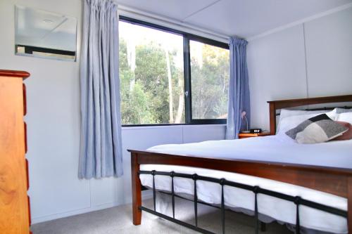 a bedroom with a bed and a large window at The Bird House Tiny Home in Ngaruawahia