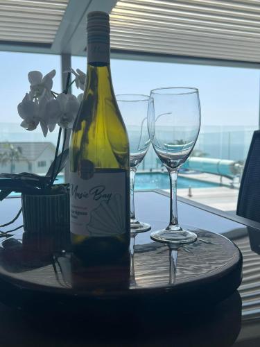 a bottle of wine and two wine glasses on a table at Eagle View in Cable Bay