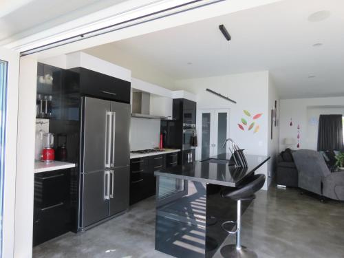 a kitchen with black cabinets and a stainless steel refrigerator at Eagle View in Cable Bay