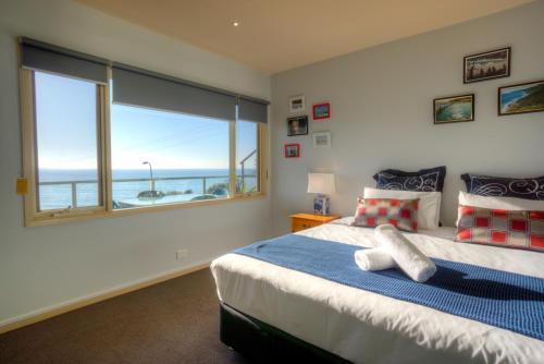 a bedroom with a bed and a large window at Pierview Apartments in Lorne