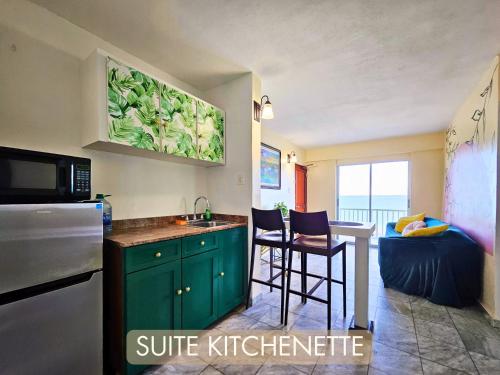 Selva Boutique Hotel - Luquillo Oceanfront Retreat في لوكويللو: مطبخ مع دواليب خضراء ومغسلة في الغرفة