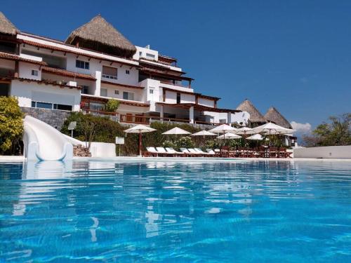 a swimming pool in front of a hotel with umbrellas at PLAYA PRIVADA del desarrollo in Ixtapa