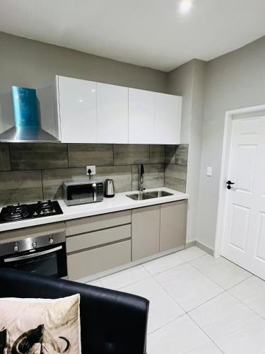 a kitchen with white cabinets and a sink and a stove at Coastal Bliss at Ongwe in Swakopmund