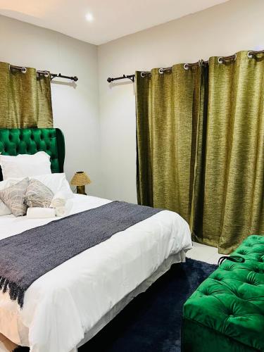 a bedroom with a large bed and green curtains at Coastal Bliss at Ongwe in Swakopmund
