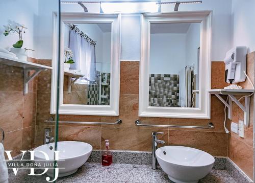 een badkamer met 2 wastafels, een bad en 2 spiegels bij Rooftop with Pool, La Romana, Villa Doña Julia in La Romana