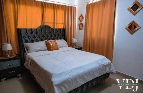 Schlafzimmer mit einem großen Bett und orangefarbenen Vorhängen in der Unterkunft Rooftop with Pool, La Romana, Villa Doña Julia in La Romana