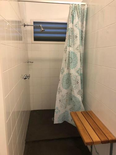 a shower with a curtain and a bench in a bathroom at Omeo Holiday Park in Omeo