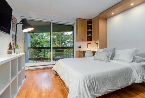 a bedroom with a white bed and a large window at Casa Creekside - Walk to Gondola, Shops, lakes! in Whistler