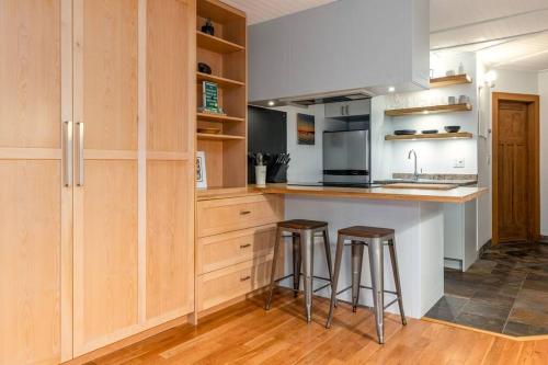 a kitchen with wooden cabinets and a counter with stools at Casa Creekside - Walk to Gondola, Shops, lakes! in Whistler