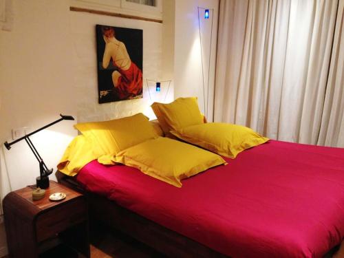 ein Schlafzimmer mit einem roten Bett mit gelben Kissen in der Unterkunft Petit luxe à la française - Paris Levallois à 15' des Champs Elysées in Levallois-Perret