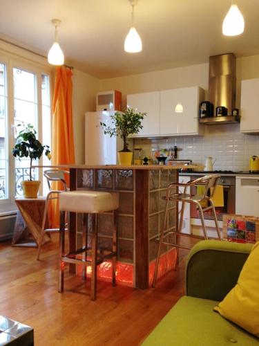 une cuisine avec un comptoir, des chaises et une table dans l'établissement Petit luxe à la française - Paris Levallois à 15' des Champs Elysées, à Levallois-Perret