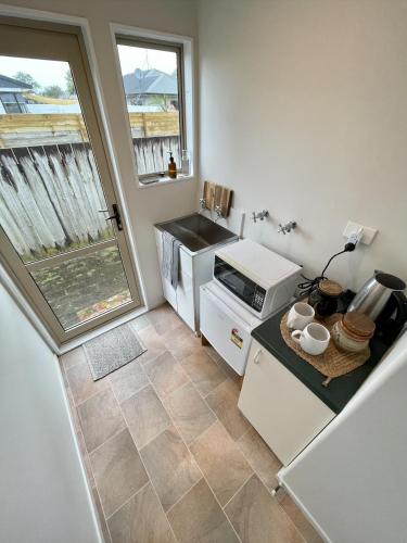 a small kitchen with a sink and a microwave at Papamoa Two Rooms & Kitchenette - Dogs welcome in Papamoa