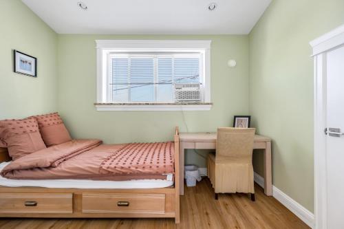 Schlafzimmer mit einem Bett, einem Schreibtisch und einem Fenster in der Unterkunft Three bedrooms brand new laneway house near public transit in Vancouver