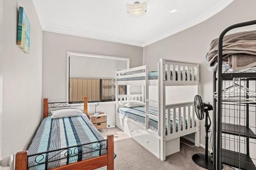 a bedroom with two bunk beds and a window at Beach Duplex 72 Marine Dr - Fingal Bay in Fingal Bay