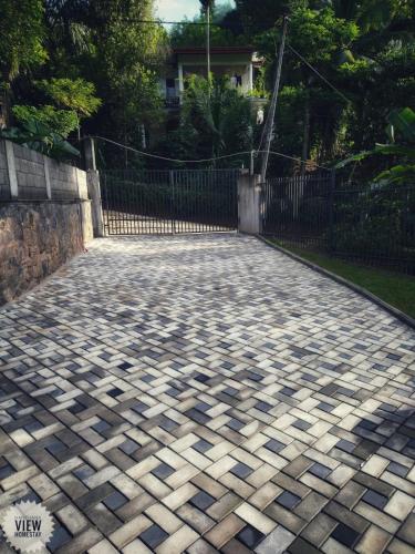 a cobblestone road with a fence in a yard at Hanthana View Homestay in Kandy