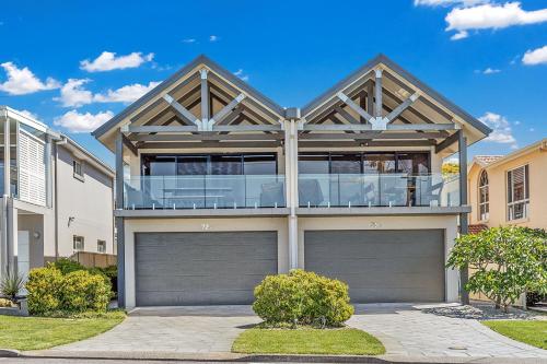 a house with two garage doors and a balcony at Beach Duplex 72 Marine Dr - Fingal Bay in Fingal Bay