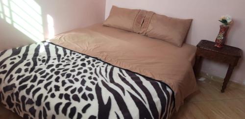 a bed with a black and white comforter and a table at A 5 minutos del aeropuerto de fes in Oulad Tayeb