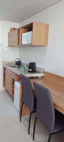 a kitchen with two chairs and a counter with a microwave at Granja Brasil - Itaipava in Petrópolis