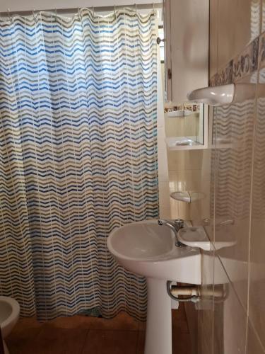 a bathroom with a sink and a shower curtain at Cabañas Las Pencas in Mina Clavero