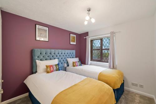 2 łóżka w pokoju o kolorze fioletowym i żółtym w obiekcie Beautiful 5 bedroom house in Stone, Aylesbury, Free parking w mieście Stone