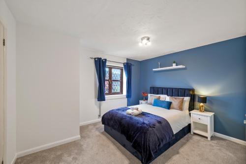 a blue bedroom with a bed and a window at Beautiful 5 bedroom house in Stone, Aylesbury, Free parking in Stone
