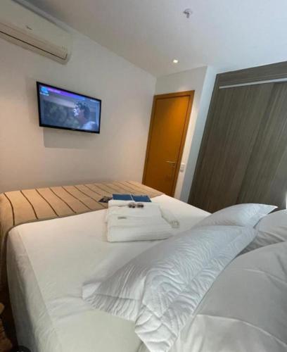 um quarto com uma cama branca e uma televisão na parede em Suítes Samba Convention no Rio de Janeiro