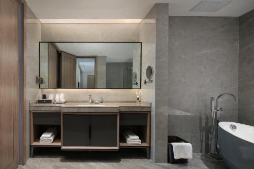 a bathroom with a sink and a mirror and a tub at NATIONAL SCENIC SPOT SUNSHINE RESORT HOTEL in Zhangjiajie