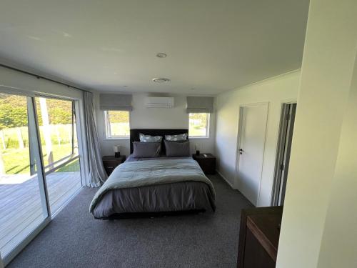 Schlafzimmer mit einem Bett und einer Glasschiebetür in der Unterkunft Kiwi Retreat in Kerikeri