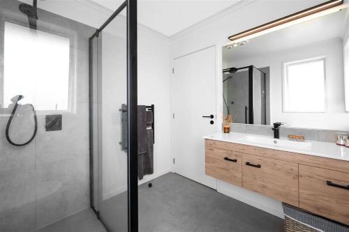 ein Bad mit einer Dusche, einem Waschbecken und einem Spiegel in der Unterkunft Kiwi Retreat in Kerikeri