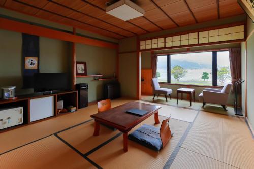 a living room with a table and a tv at Jinpuso in Miyazu